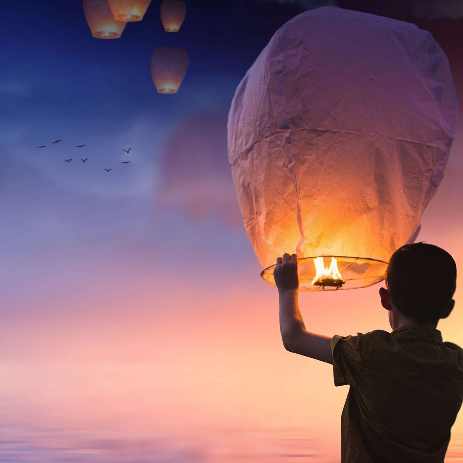 happy child setting a lantern into the night air