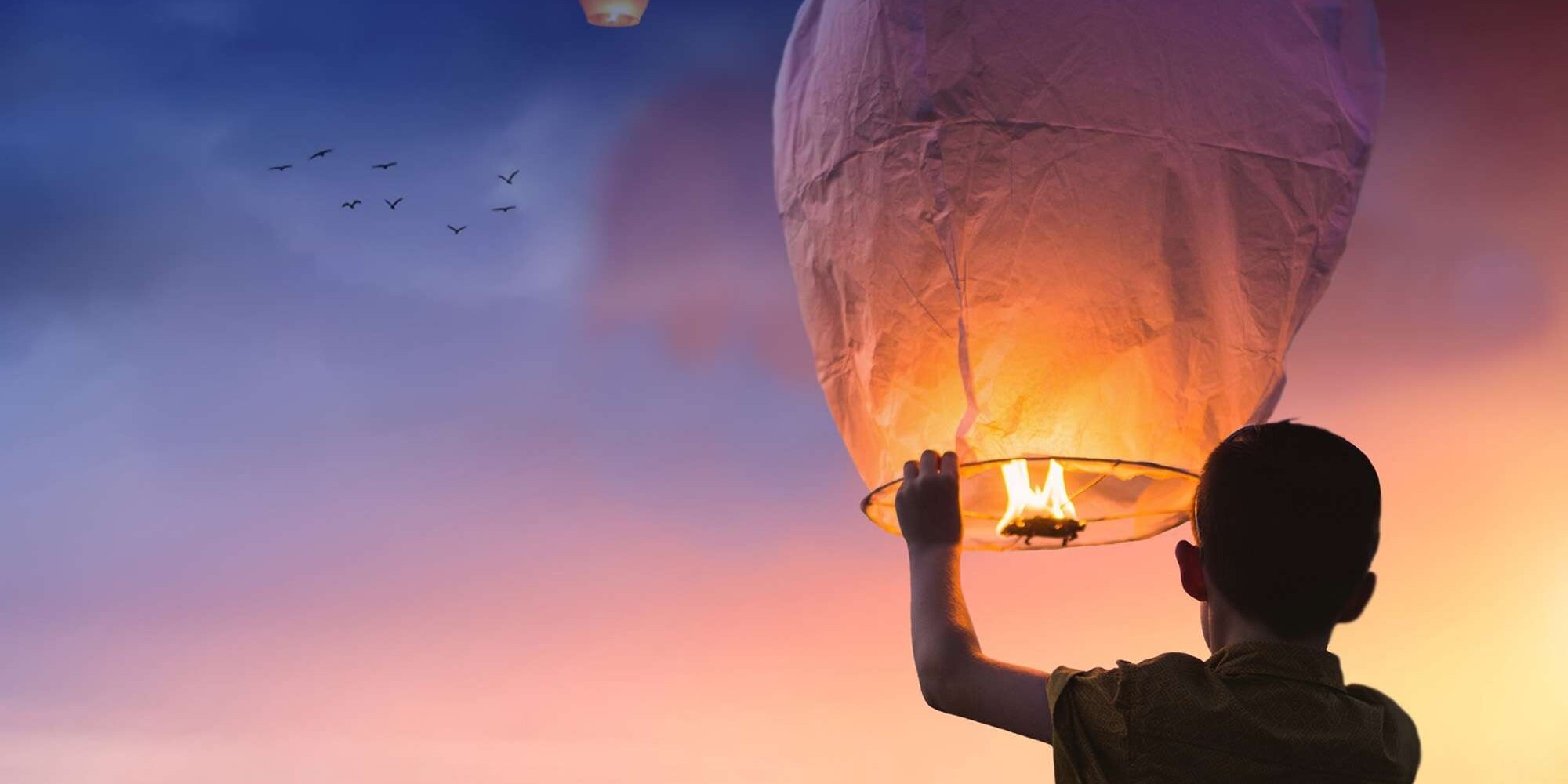 happy child setting a lantern into the night air