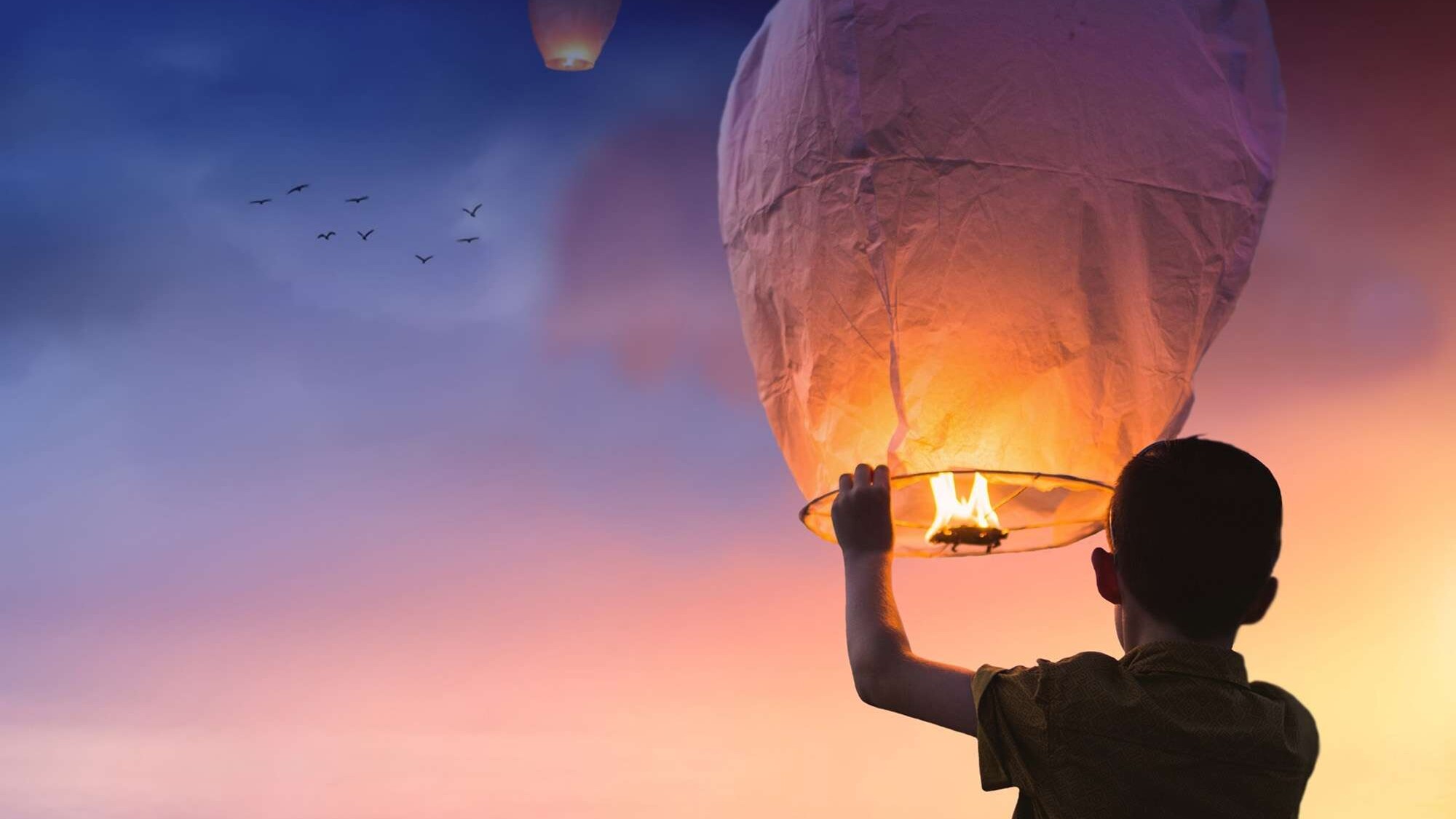 happy child setting a lantern into the night air