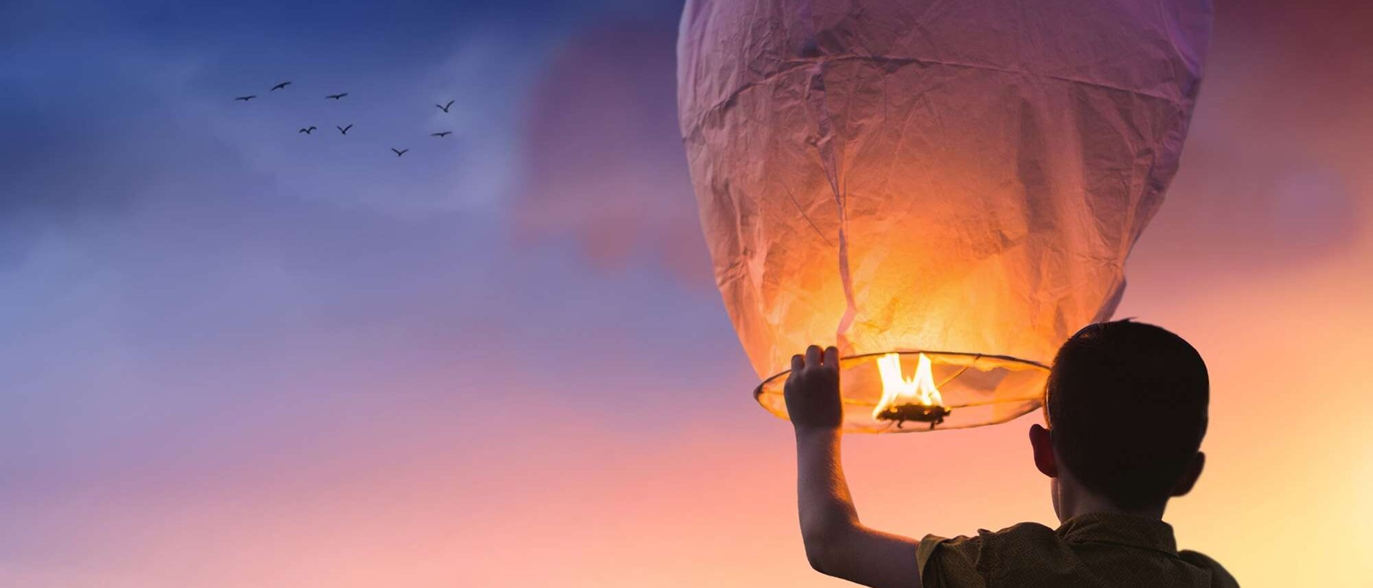 happy child setting a lantern into the night air